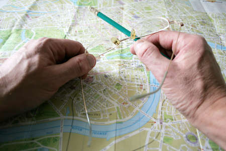 hand with pencil and geographical card to terrain