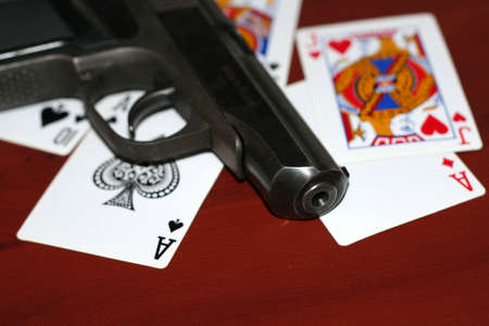 gun and playing cards on table in casinoのeditorial素材