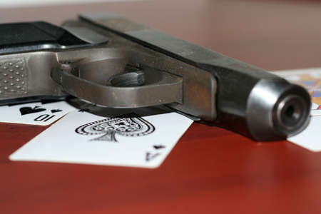 gun and playing cards on table in casinoのeditorial素材