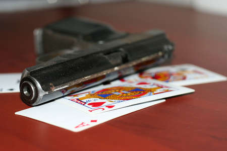 gun and playing cards on table in casinoのeditorial素材
