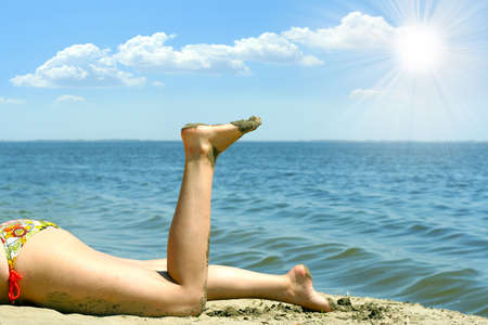 feminine legs on background sand beach