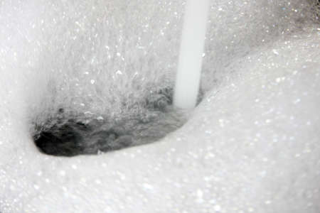 white foam bubbles on the surface of flowing waterの写真素材