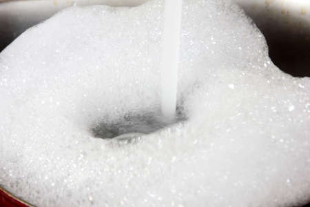 white foam bubbles on the surface of flowing waterの写真素材