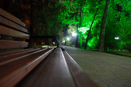 image wooden bench in a tropical park and pedestrian roadの写真素材