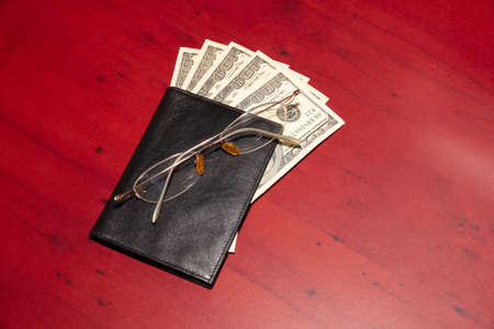 leather purse, old glasses and paper dollars