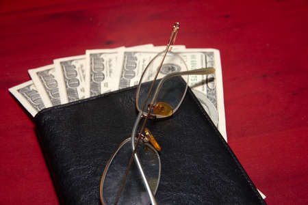 leather purse, old glasses and paper dollarsの写真素材