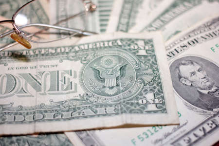 glasses for vision correction and a small pile of dollarsの写真素材