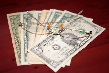 glasses for vision correction and a small pile of dollarsの写真素材