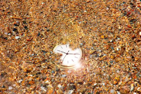 gold watch and sand of the sea on the coastの写真素材