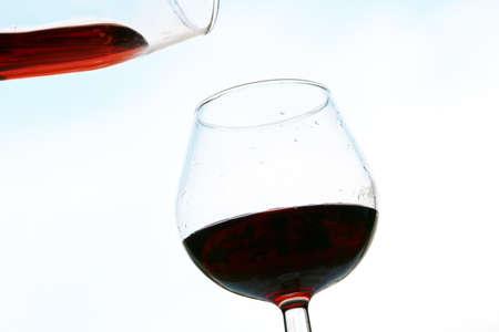 bright red liquid flowing into a glass from a jugの写真素材