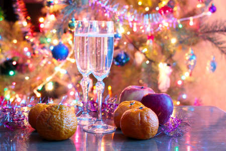 Glasses of wine, tangerine and apple on Christmas tableの写真素材