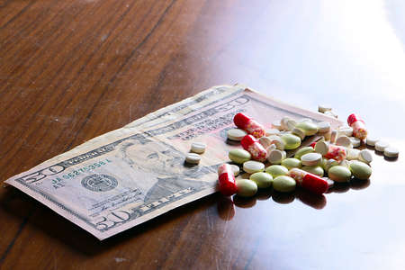 Dollar paper banknotes and medicine drugs and tablets as part of paid health care and treatmentの写真素材
