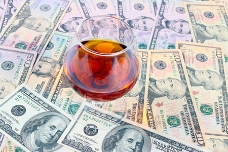 glass of strong alcoholic drink and a heap of paper dollars billsの写真素材