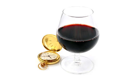 glass of strong red wine and pocket watch in gold case as a symbol of good luck and successの写真素材