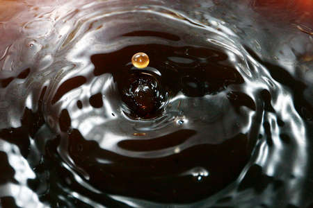 A drop of water creates fantastic patterns when falling on the surface of a liquidの写真素材
