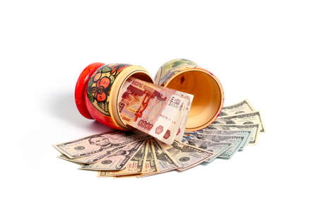 Russian national wooden toy with paper bills standing on a pile of American dollarsの写真素材