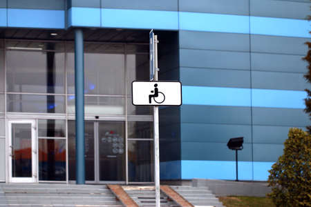 A parking place for disabled people equipped with indicative car signs parked near a public buildingの写真素材