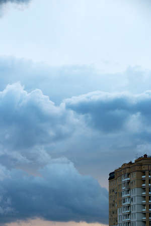 Thick dark evening clouds to the sky and wall of the building