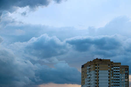 Thick dark evening clouds to the sky and wall of the buildingの写真素材