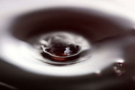 A drop of water on the surface of a liquidの写真素材