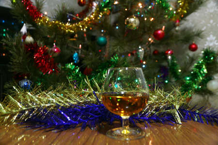 A glass of wine and strong alcohol on the background of a festive New Year's decorationの写真素材