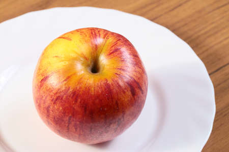 beautiful ripe fresh apple on a white plateの写真素材