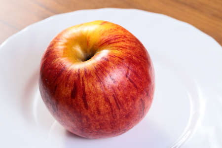 beautiful ripe fresh apple on a white plateの写真素材
