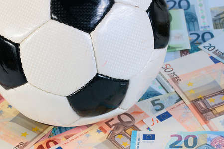 beautiful leather soccer ball lies on a pile of paper euro billsの写真素材