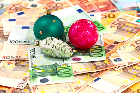 Beautiful glass Christmas tree toys and a pile of paper euros as a giftの写真素材