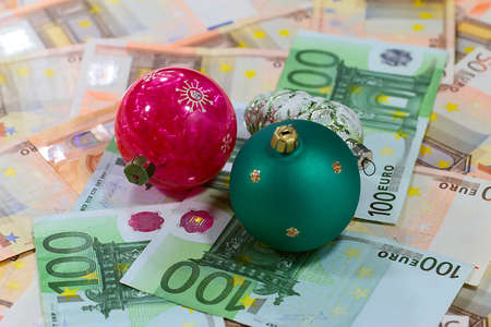 Beautiful glass Christmas tree toys and a pile of paper euros as a giftの写真素材