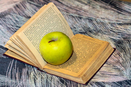 a ripe fresh apple on the pages of an old bookの写真素材