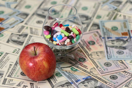 fresh apple and medicine on paper denominations dollars