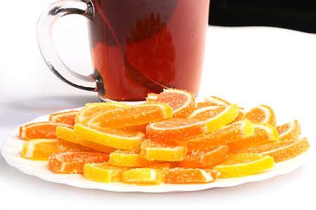pieces of sweet marmalade on a plate next to a cup of strong hot tea