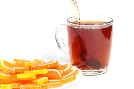 pieces of sweet marmalade on a plate next to a cup of strong hot teaの写真素材