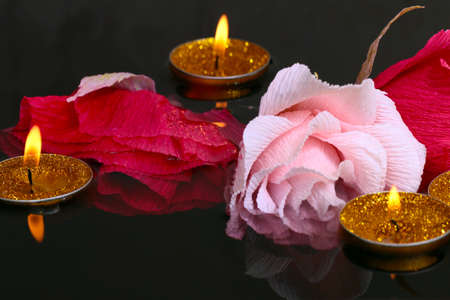 bright candle flame and paper rose flowers on the water surfaceの写真素材