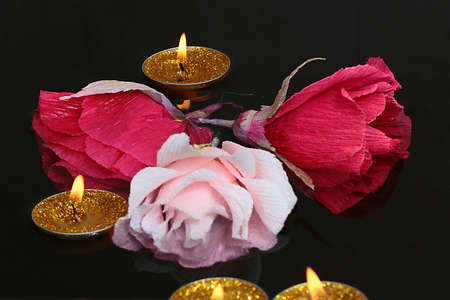 bright candle flame and paper rose flowers on the water surfaceの写真素材