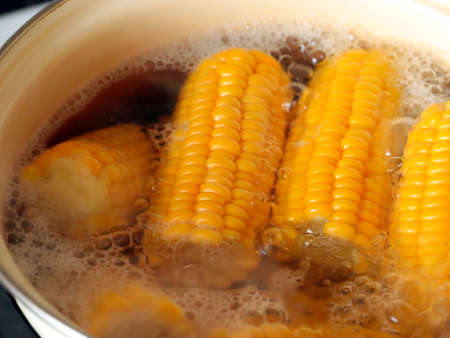 ripe fresh corn in boiling water while cooking for foodの写真素材