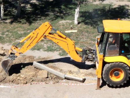 construction excavator cleans road curbs during reconstruction