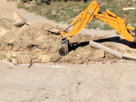 construction excavator cleans road curbs during reconstruction