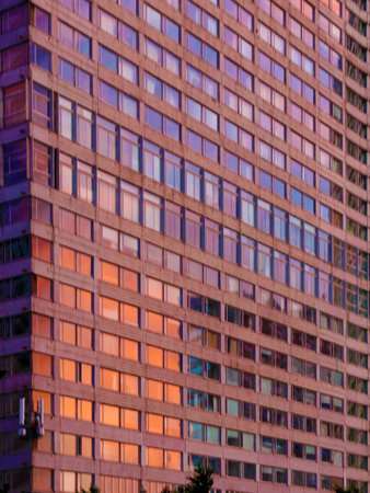 A vertical shot of a modern office building with windows in the evening
