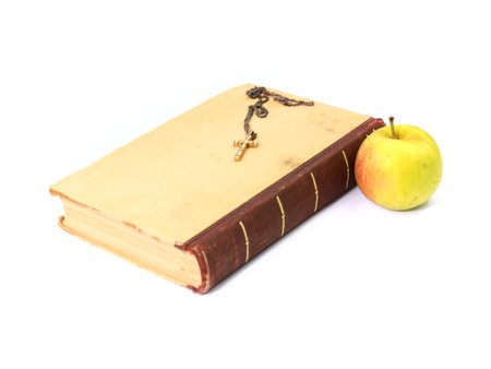 a ripe apple lies next to an ancient book and a Christian crossの写真素材