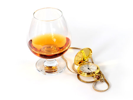 a pocket watch in a gold case and a glass of spiritsの写真素材
