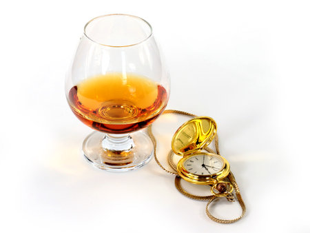a pocket watch in a gold case and a glass of spiritsの写真素材