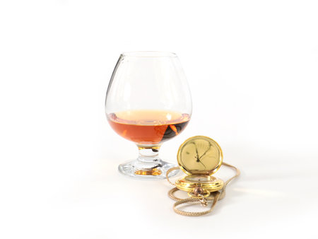 a pocket watch in a gold case and a glass of spiritsの写真素材