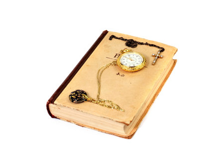 an old book and a cross with an antique pocket watch