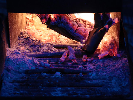 a brightly burning fire and ashes in the loading window of the boiler room stoker