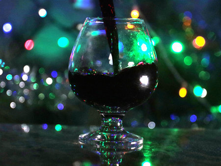 a stream of red wine when poured into a glass on an illuminated background
