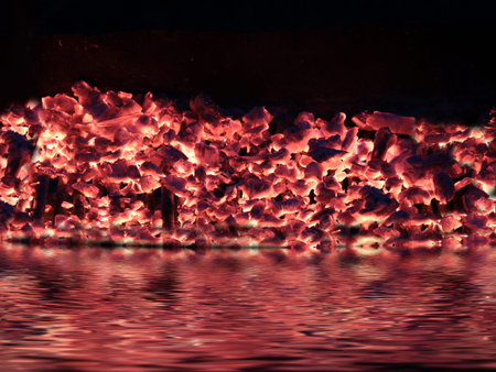 the red-hot coal fire is reflected in the water surfaceの写真素材