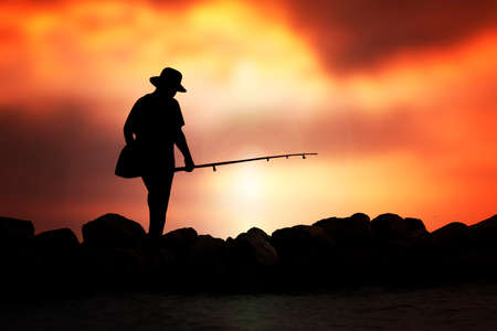 Silhouette of man fishing rod sunset background.の写真素材