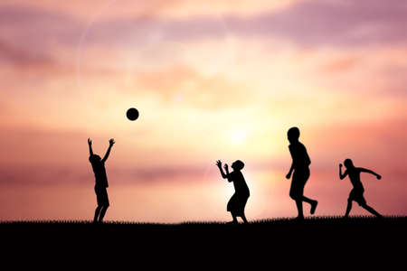 Silhouette of children playing soccer background skyの写真素材